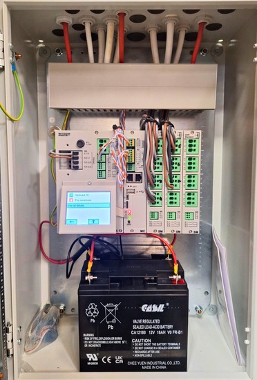 Close-up of smoke control system panel with installed lead-acid battery and terminal wiring for emergency power supply.